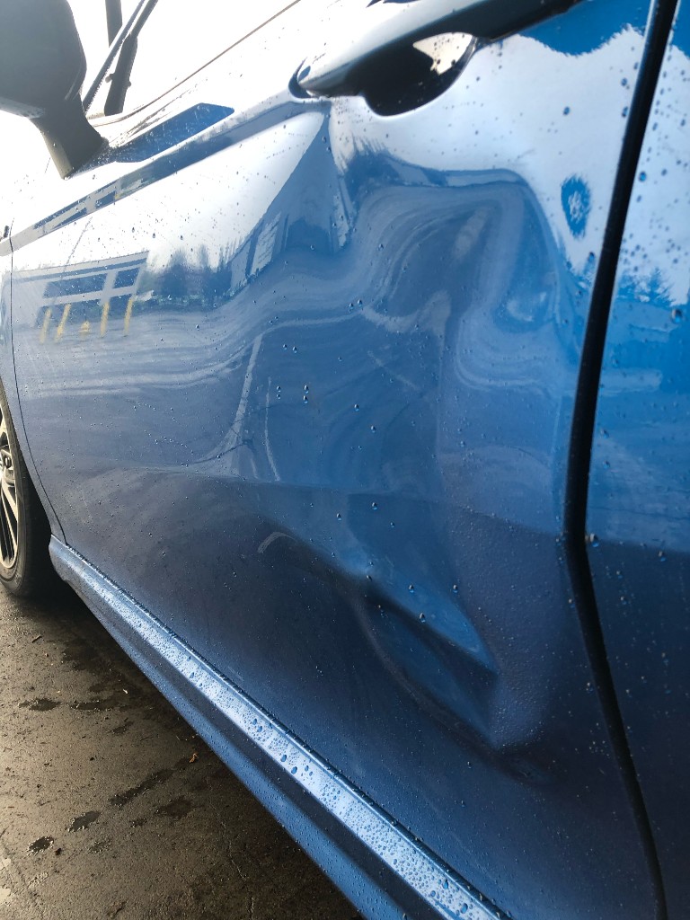 Before repair - blue car door panel dent