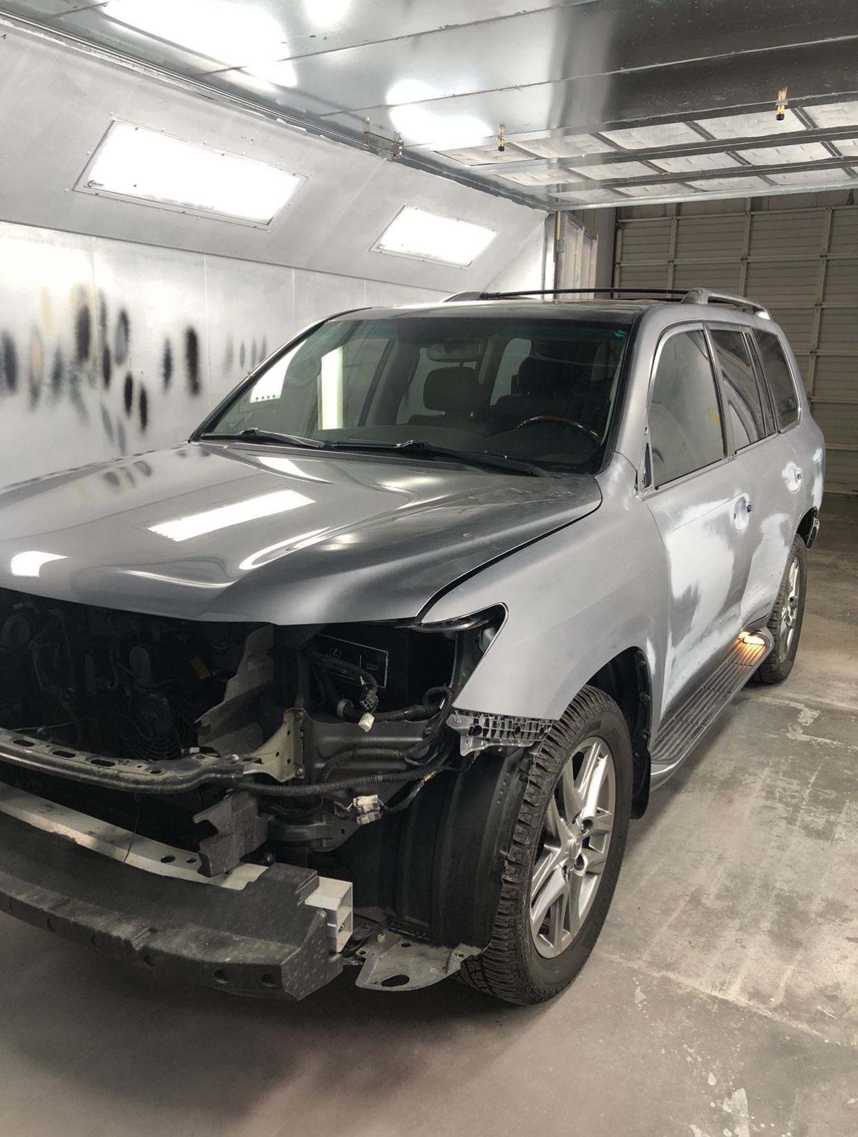 Before repair - SUV in paint booth with bumper removed